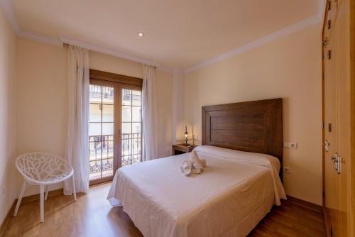 ein Schlafzimmer mit einem Bett, einem Fenster und einem Stuhl in der Unterkunft Apartamento Céntrico Sibarys - 1 dormitorio- Calle Pintada in Nerja