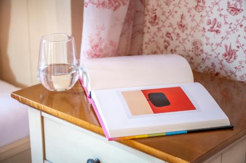 a book sitting on a table with a glass at Hotel Garni Villa Rosengarten in Überlingen