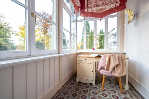 ein Heimbüro mit einem Schreibtisch und Fenstern in der Unterkunft Hotel Garni Villa Rosengarten in Überlingen
