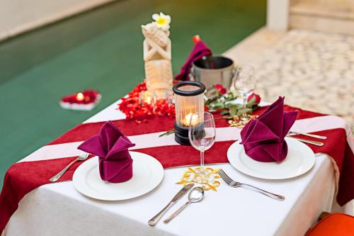 a table with two white plates and purple napkins at Villa Kayu Raja in Seminyak