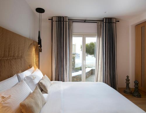a bedroom with a bed and a large window at Vencia Boutique Hotel in Mýkonos City