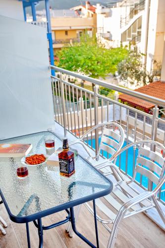 a glass table on a balcony with a bottle of alcohol at RENT HOUSE ANEMOS in Iraklitsa