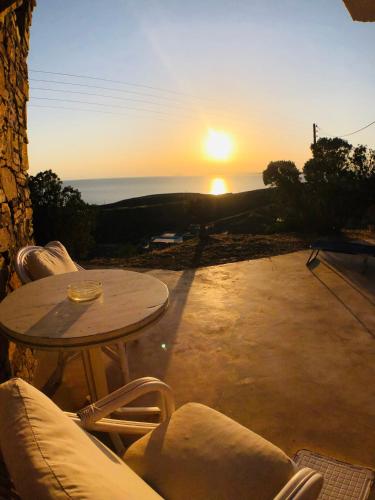 a table and chairs with the sunset in the background at The Stone Windmill in Koundouros