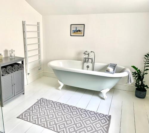 Baño blanco con bañera y alfombra en Stunning 3 bed house in the heart of Cheltenham, en Cheltenham