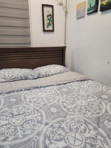 Ilia's Cozy Abode near Enchanted Kingdom & Nuvali في سانتا روزا: سرير في غرفة نوم مع لحاف عليه