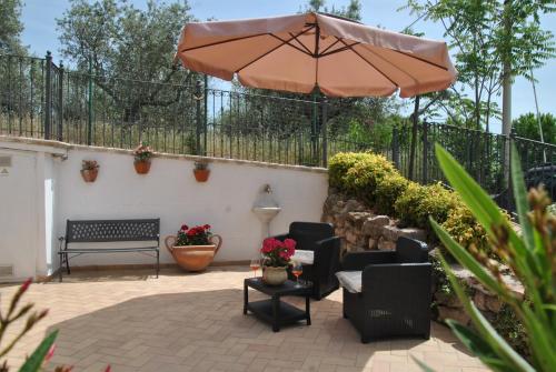a patio with an umbrella and chairs and a bench at Appartamenti Elisa in Assisi