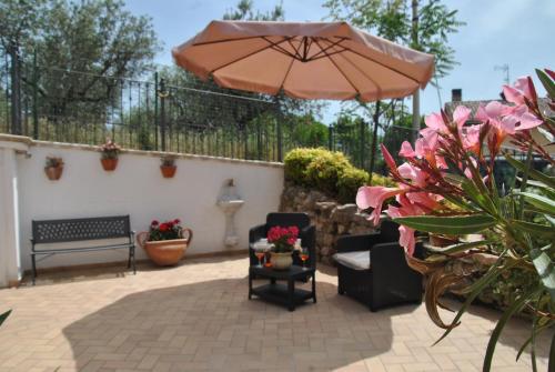 a patio with an umbrella and furniture and flowers at Appartamenti Elisa in Assisi