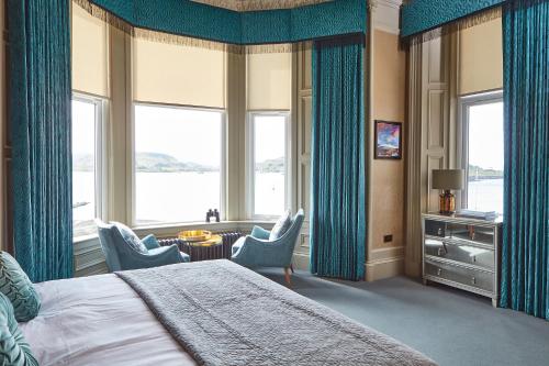 a bedroom with blue curtains and a bed and a table and chairs at No17 The Promenade in Oban