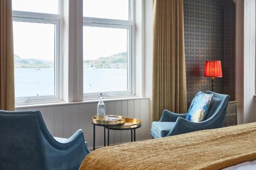 a hotel room with a bed and chairs and windows at No17 The Promenade in Oban