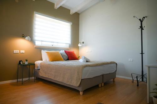a bedroom with a bed with pillows and a window at Tslil Suite in Yeroẖam