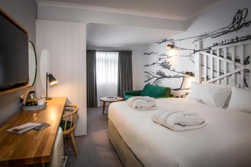 um quarto de hotel com uma grande cama branca e uma secretária em North Lakes Hotel and Spa em Penrith
