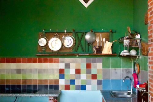 una cocina con una pared verde con ollas y sartenes en Tầm Quên Homestay, en Tây Ninh
