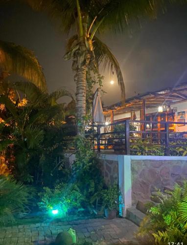 a resort with a palm tree and a pool at night at Villa Mistika in Zorritos