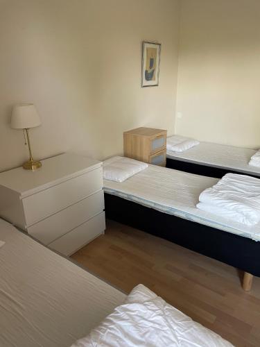 a room with three beds and a lamp in it at Björkbackens Vandrarhem i Vimmerby in Vimmerby