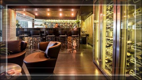 a bar with leather chairs and a woman in the background at Sukhumvit Suites Hotel in Bangkok