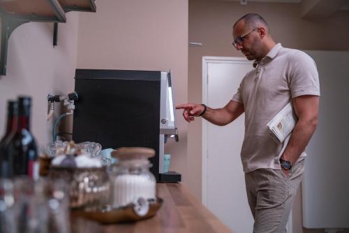 a man standing in a kitchen pointing at a machine at Hotel Janssen in Valkenburg