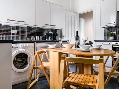 a white kitchen with a wooden table and chairs at Maple House - Quaint Victorian Home With Free Parking in York