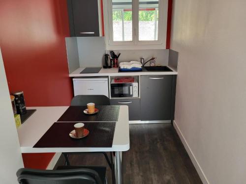 - une petite cuisine avec une table et deux tasses dans l'établissement Un bel appartement proche centre ville et 20 mn du Puy du Fou, à Cholet