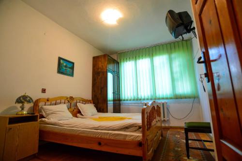 a bedroom with a bed with a wooden frame and a window at Topuzovi Guest House in Dobrinishte