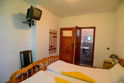 a bedroom with two beds and a tv on the wall at Topuzovi Guest House in Dobrinishte