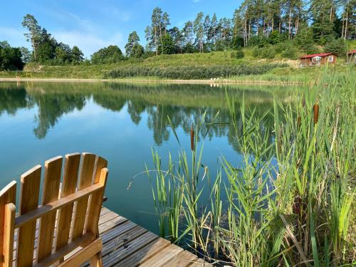 a wooden bench sitting on a dock next to a lake at Między Wodami - domki na Mazurach in Mikołajki
