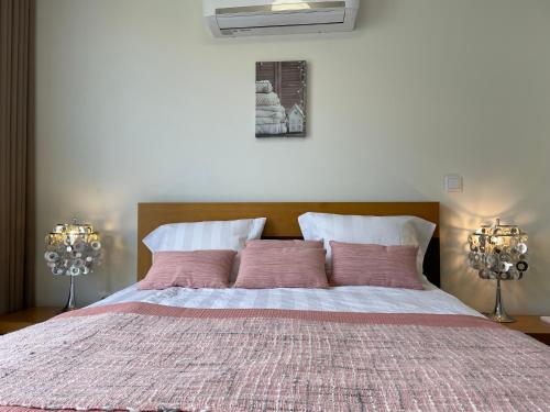 um quarto com uma cama grande e almofadas cor-de-rosa em Vila Inês - Beautiful 2 bedroom villa with private pool and stunning views of the Atlantic Ocean em Arco da Calheta