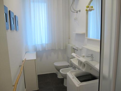 a white bathroom with a toilet and a sink at Appartamento Ariston in Lido