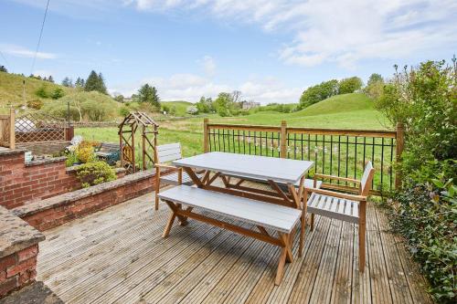 Host & Stay - Ramblers Rest Cottage في Greenhead: طاولة نزهة وكرسيين على سطح خشبي