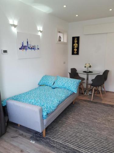 a bedroom with a bed with blue sheets and a table at Star London Brent Street Cosy 1-Bed Hideaway in Hendon