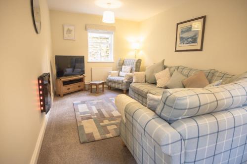a living room with a couch and a tv at Middle Row Cottage in Richmond