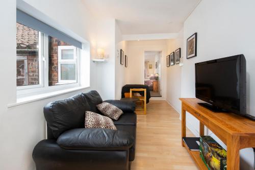 a living room with a black leather couch and a flat screen tv at Stable Lofts in York