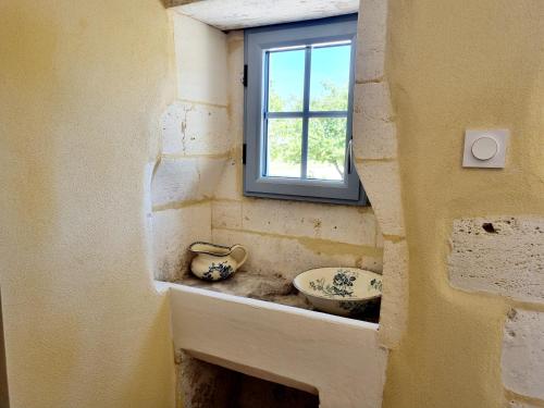a bathroom with a sink and a window at Fleurs de vigne, gîte charentais au grand coeur in Bouteville