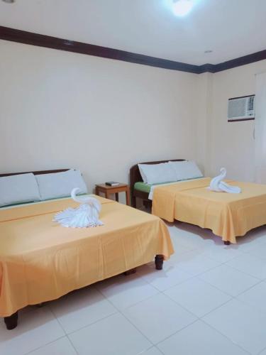 two beds in a room with yellow sheets at Villa Almedilla Pension House in Panglao Island