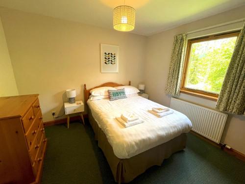 a bedroom with a bed with a dresser and a window at Pass the Keys Beautiful 3BR Lodge - Stunning Beach and Golf Location in Dalbeattie