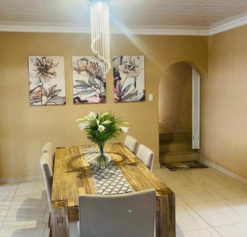 a dining room table with a vase of flowers on it at Erins Haven - Polokwane in Polokwane