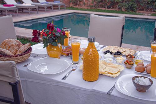 una mesa con comida y bebida junto a una piscina en Villa Atlas Secret, en Ourika