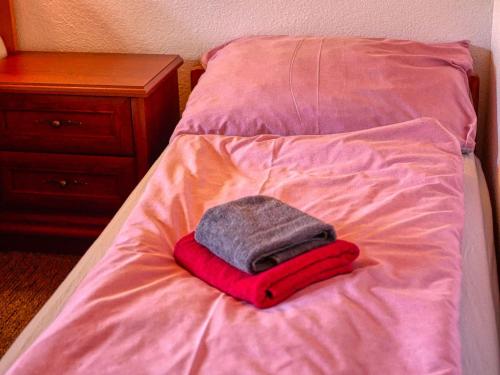 a bed with a red blanket and a towel on it at Penzión Hron - Beňuš in Beňuš