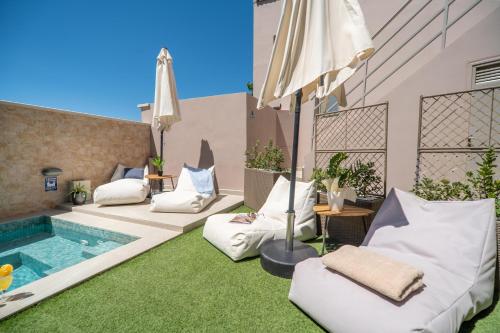 a patio with pillows and an umbrella and a pool at Aegean Breeze Luxury Apartments next to the sea in Maleme