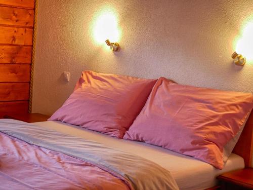 a bed with two pillows and two lights on the wall at Penzión Hron - Beňuš in Beňuš