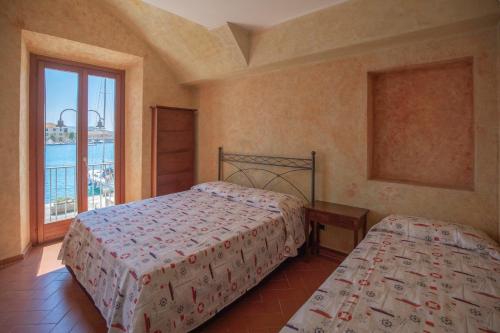 a bedroom with two beds and a large window at Appartamento Lungomare - HelloElba in Portoferraio