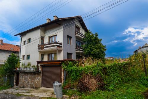 a white building with a garage in front of it at Topuzovi Guest House in Dobrinishte
