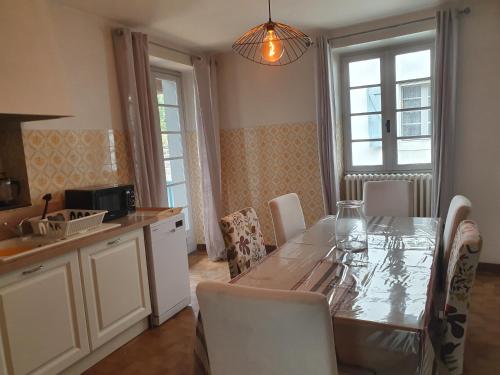 een keuken met een tafel en stoelen en een keuken met ramen bij Gîtes Saint-Pierre in Oloron-Sainte-Marie
