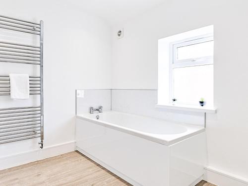 a white bathroom with a sink and a window at Pass the Keys Luxury Bright Spacious Family Home - Near Beaches in Swansea