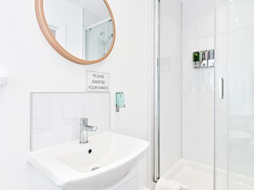 a white bathroom with a sink and a mirror at Pass the Keys Luxury Bright Spacious Family Home - Near Beaches in Swansea
