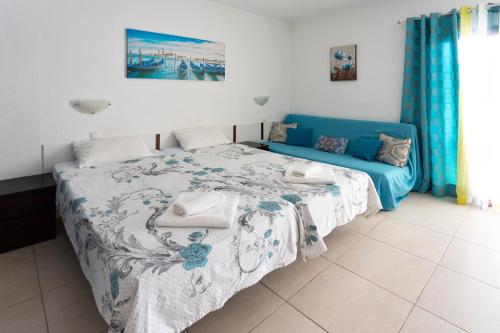 ein Schlafzimmer mit einem Bett und einem blauen Sofa in der Unterkunft Ocean View Studio in Adeje
