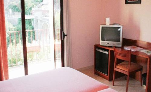 a bedroom with a bed and a desk with a television at Hotel Sant Quirze De Besora in Sant Quirze de Besora