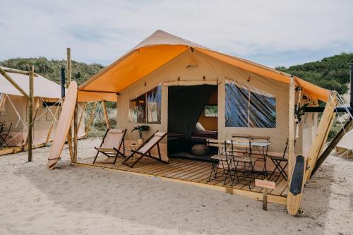 a tent on the beach with a table and chairs at Beachcamp Bloemendaal Surf Resort in Overveen
