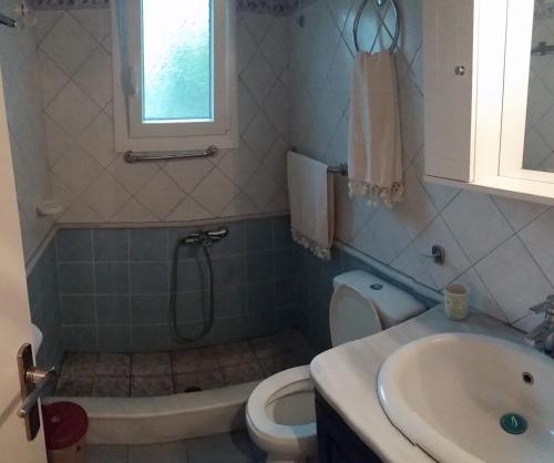 La salle de bains est pourvue d'une baignoire, d'un lavabo et de toilettes. dans l'établissement By the sea, à Andros