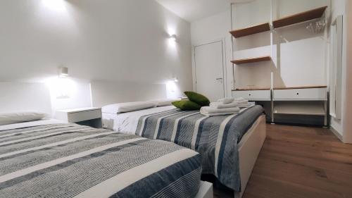 2 letti in una camera con pareti bianche e pavimenti in legno di B&B Va' Pensiero a Villasimius
