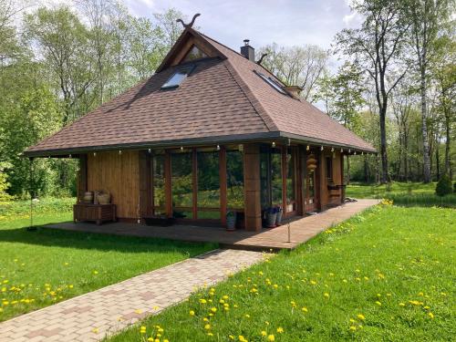 a large gazebo with a roof in a park at UpeNes in Lubāna